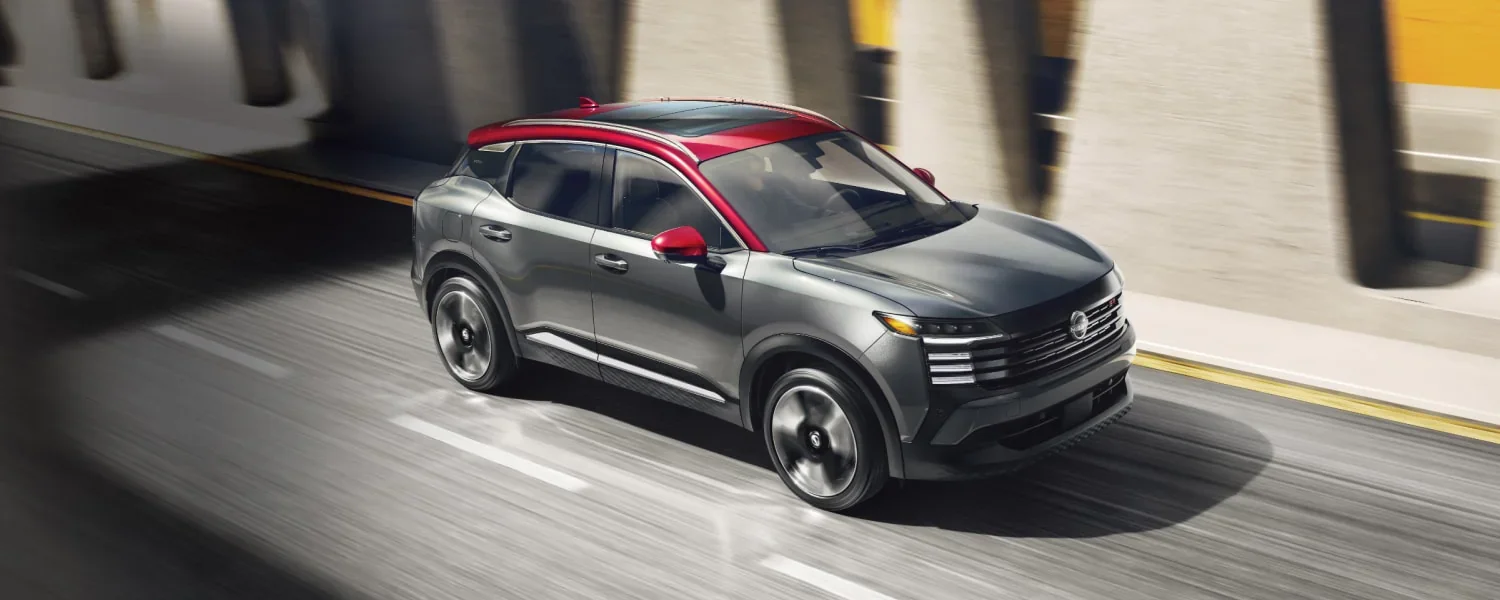 gray and red nissan kciks driving down a road